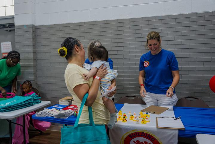 A parent holding her baby while a partner organization explains its services