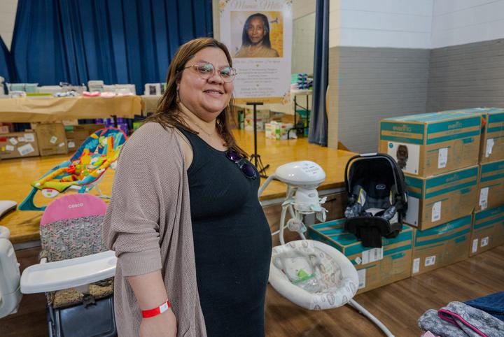 An expecting mom beside car seats and baby gear
